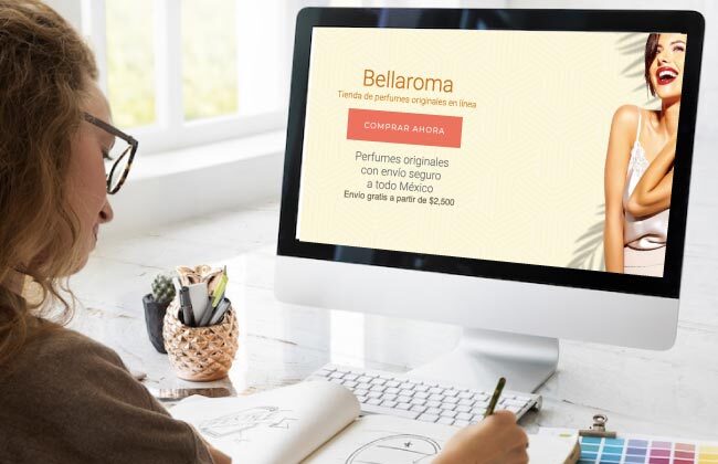Mujer trabajando en línea con pc enfrente y vista de la página de inicio de Bellaroma tienda de perfumes