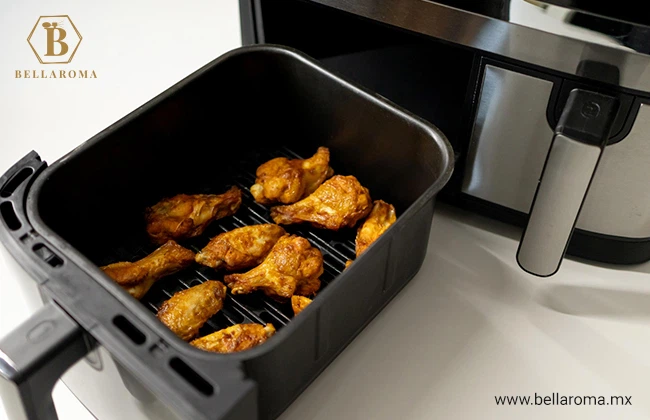 Charola de una freidora de aire con alitas de pollo recién hechas en su interior, este es uno de los detalles para papá más originales