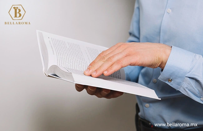 Hombre con camisa sujetando un libro abierto y separándolo con la mano