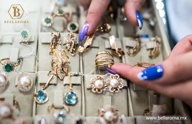 Par de manos mostrando un joyero con diversos anillos y aretes. La joyería es uno de los productos para revender que más ganancias deja.