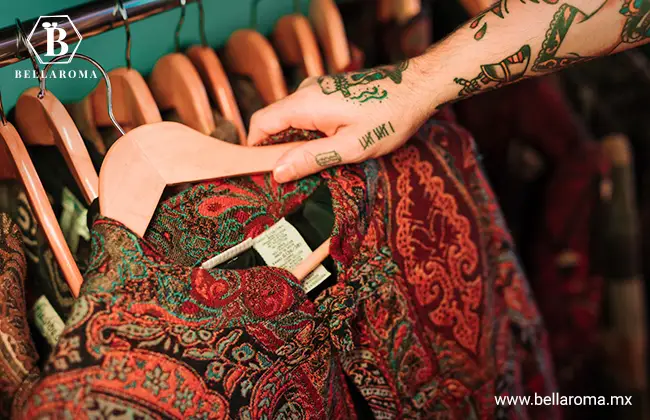 Brazo con tatuajes retirando de un perchero un vestido vintage, una de las mejores cosas por mayoreo para vender.