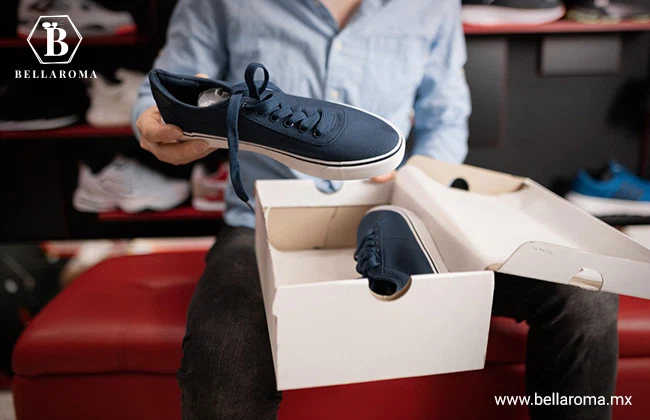 Hombre sentado mostrando unos tenis azules que se encuentran en una caja de cartón.