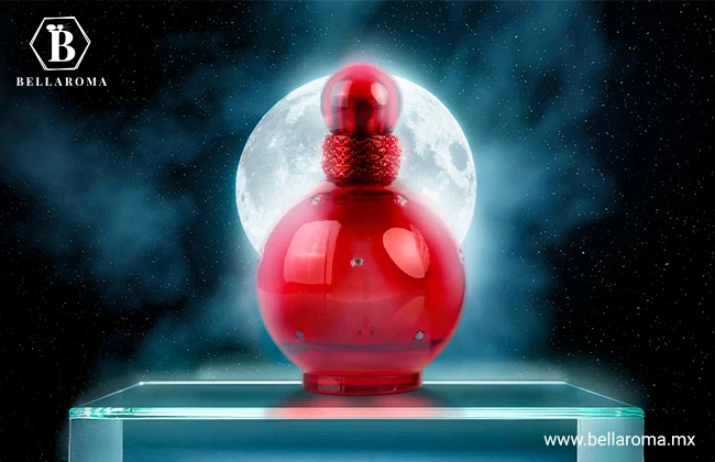 Frasco rojo redondo de Hidden Fantasy de Britney Spears con tapa esférica, colocado frente a una luna llena con fondo nocturno.