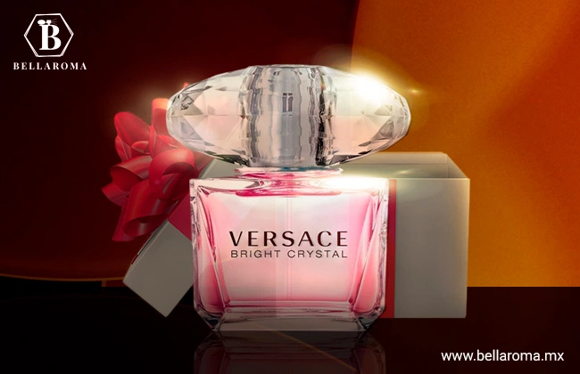 Frasco pequeño con tapa ovalada de cristal, de perfume Versace en frente de caja de regalo.