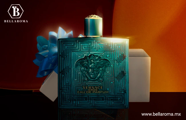 Perfume para regalar de hombre Eros de Versace color turquesa y detalles en relieve, sobre fondo oscuro y anaranjado y delante de una caja de regalo.