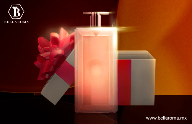 Frasco rectangular de Idole Lacome color rosa, sobre una base oscura y fondo naranja.