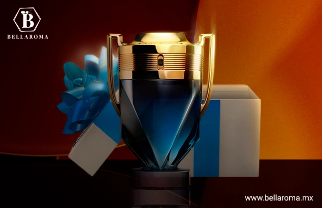 Perfume Invictus de Rabanne en forma de trofeo color azul y dorado. Sobre base plana color negro y en frente de caja de regalo con adorno azul.