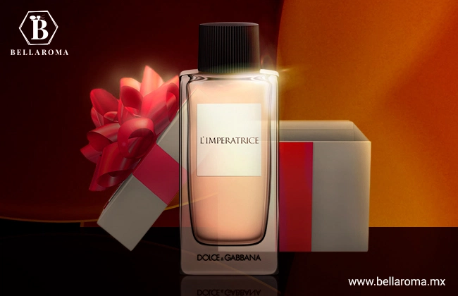 Perfume L' Imperatrice de Dolce and Gabbana de frasco rosa y tapa negra, sobre base color negro y en frente de una caja de regalo con moño rojo.