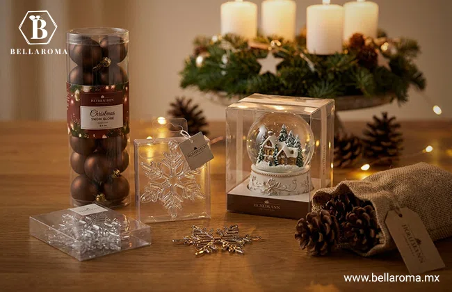 Artículos de decoración navideña, con esferas de color marrón, copos de nieve transparentes y una esfera de nieve sobre una mesa de madera.